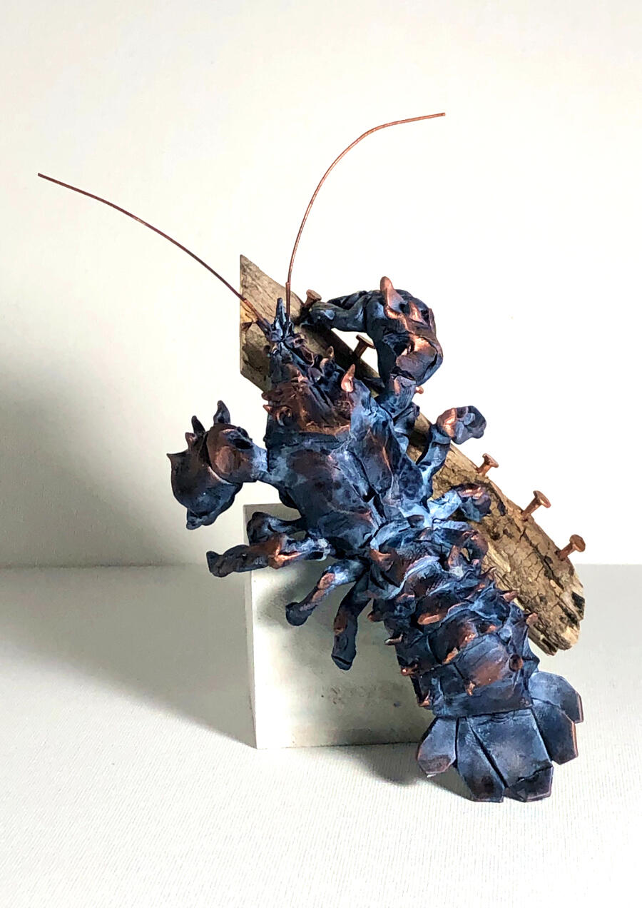 A polymer clay sculpture of a crayfish resting on a wooden cube and a foraged stick. Other materials used: copper wire, copper nails.