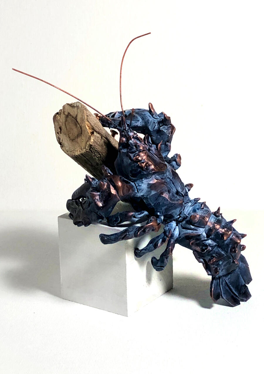 A polymer clay sculpture of a crayfish resting on a wooden cube and a foraged stick. Other materials used: copper wire, copper nails.